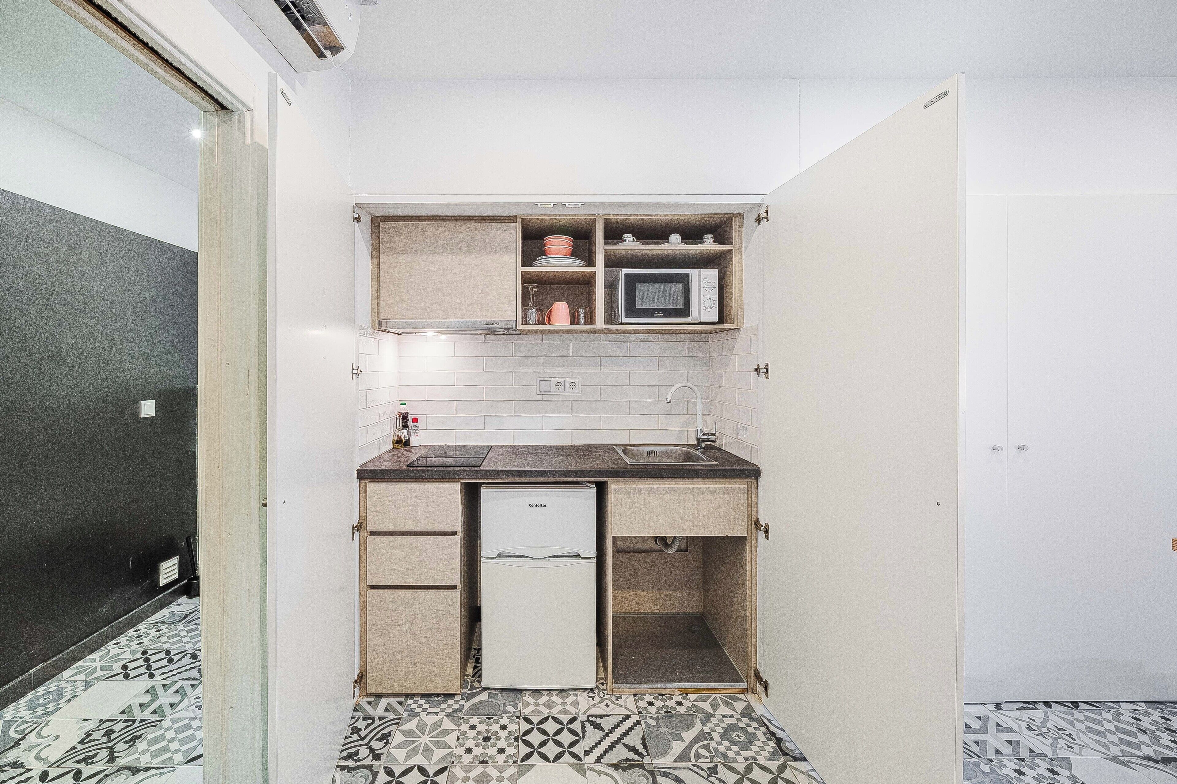A compact kitchen with a microwave, sink, and a refrigerator.