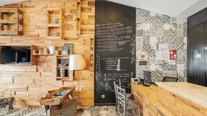 Una habitación con pared de madera, una pizarra con texto, una zona de bar y un suelo estampado.