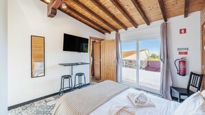 Una habitación con cama, escritorio, televisor y extintor.