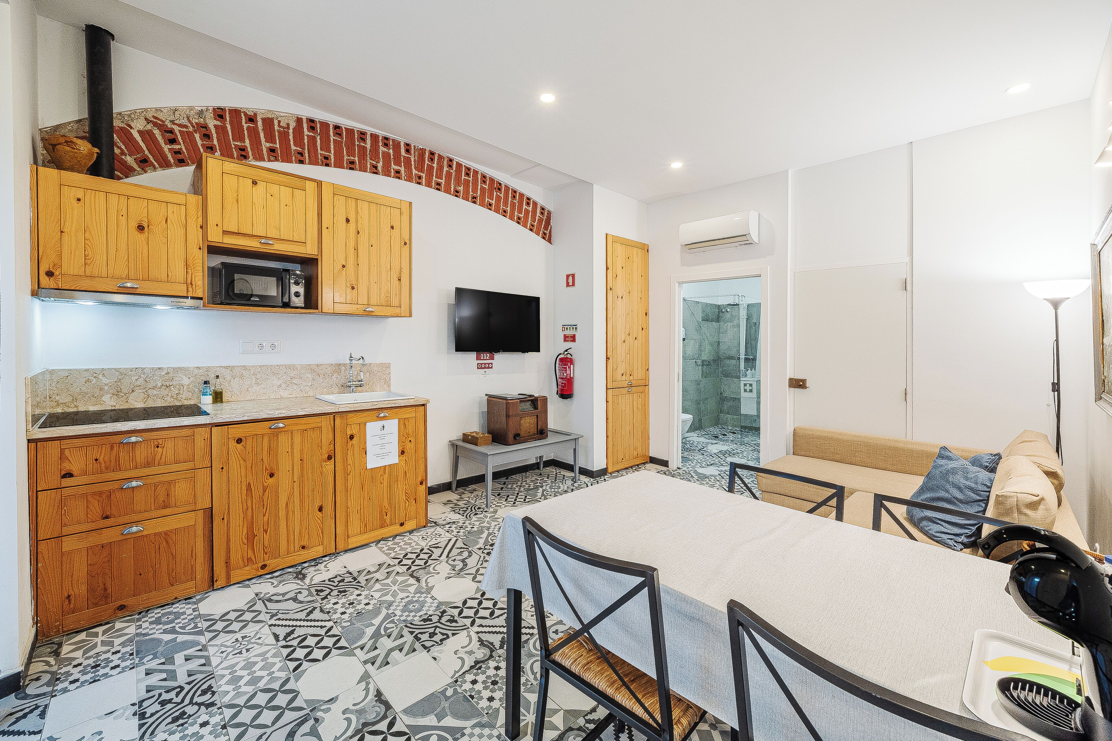 A compact kitchen with wooden cabinets, a microwave, and a television.
