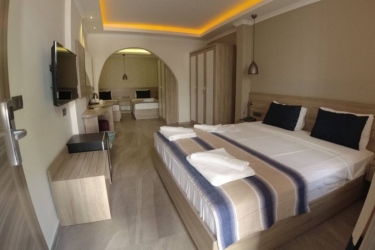 Una habitación de hotel con una cama grande, un escritorio, un espejo y un televisor.
