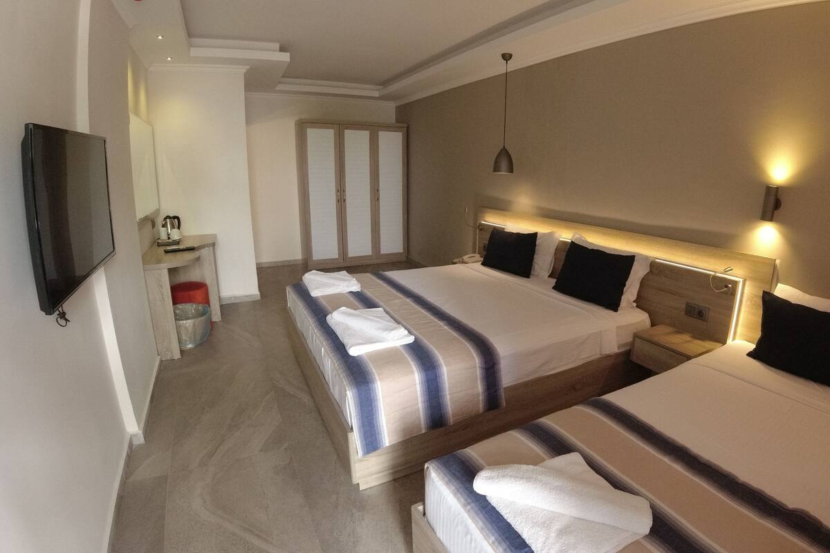Una habitación de hotel con dos camas, televisión, escritorio y armario.