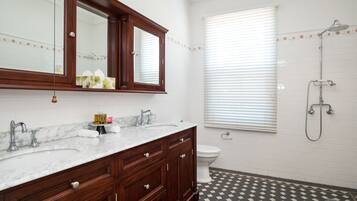 Baño con tocador de doble lavamanos, inodoro y ducha.