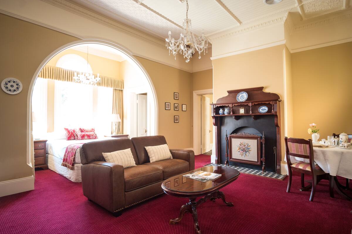 A living room with a brown leather sofa, a wooden coffee table, and a fireplace.