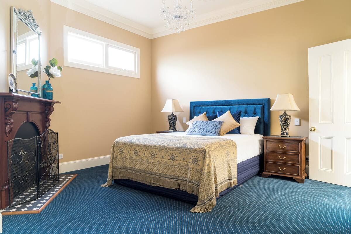A bedroom with a large bed, a dresser, a mirror, and a chandelier.