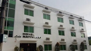 Un hotel blanco con múltiples ventanas y unidades de aire acondicionado.
