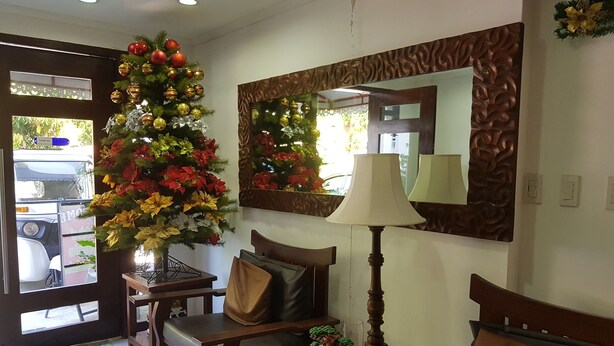 Una habitación con escritorio de madera, una silla, una lámpara, un espejo y un árbol de Navidad.