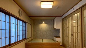 Una habitación japonesa tradicional con puertas correderas, suelo de esteras de tatami y una plataforma de madera baja.