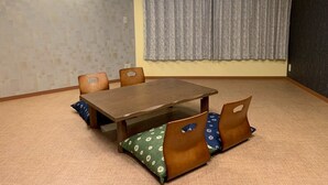 Una habitación con una mesa y sillas de madera, un equipo de aire acondicionado, una cortina estampada y una pared con textura.