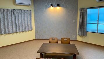 A conference room with a wooden table, four chairs, two wall-mounted lights, and a window with curtains.