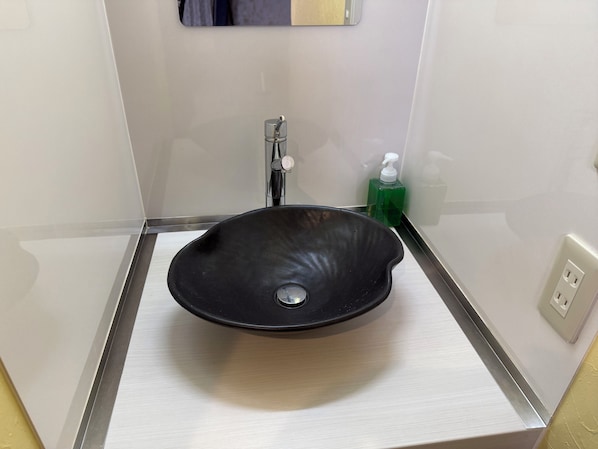 A bathroom with a black vessel sink, a faucet, and a green soap dispenser. - Hotel Prele Asakusa (Tokyo)