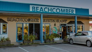 Ein Restaurant am Strand mit blauem Markisenvorzelt und großen Fenstern.