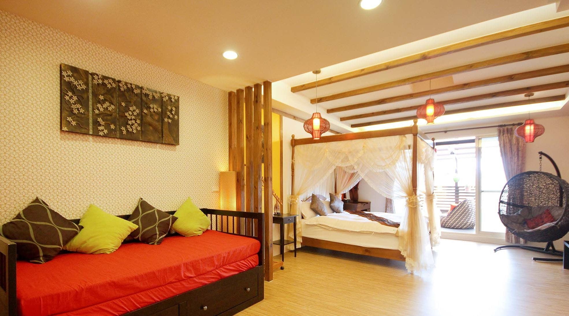 Un dormitorio con cama, sofá, sillón colgante y un amplio ventanal.