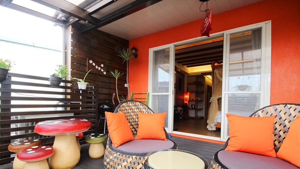 A covered outdoor seating area with wicker chairs and a table, surrounded by potted plants and a wooden fence. - Park 61 B&B (Luodong)