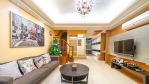 A modern living room with a sofa, coffee table, TV, and a Christmas tree. - Park 61 B&B (Luodong)
