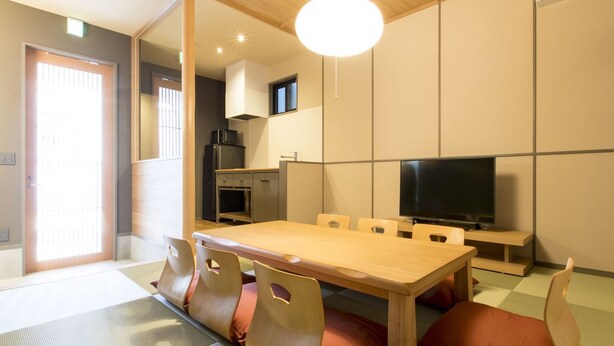Een knus woongedeelte met een eettafel, stoelen, een televisie en een kitchenette.