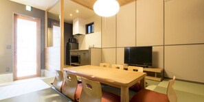 Een knus woongedeelte met een eettafel, stoelen, een televisie en een kitchenette.