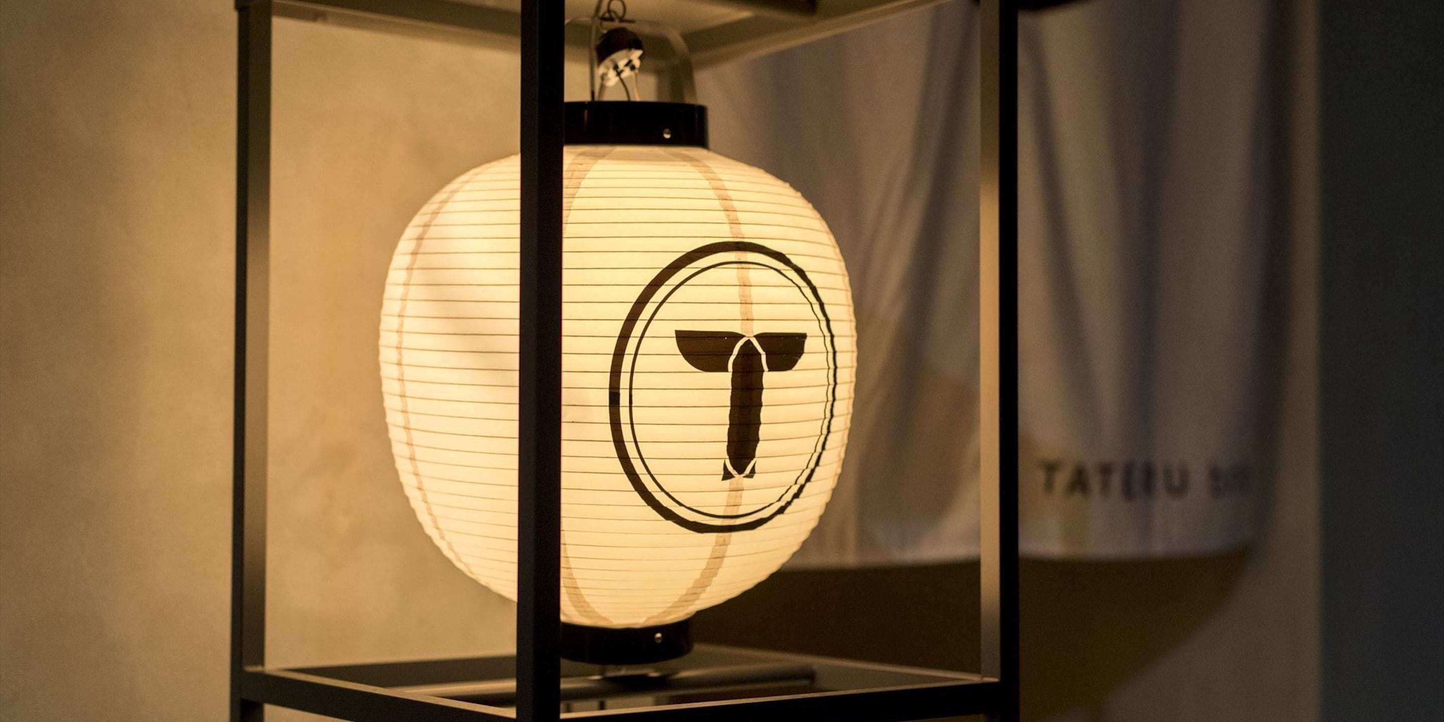 A traditional Japanese lantern with a circular design, displayed in a black-framed case.