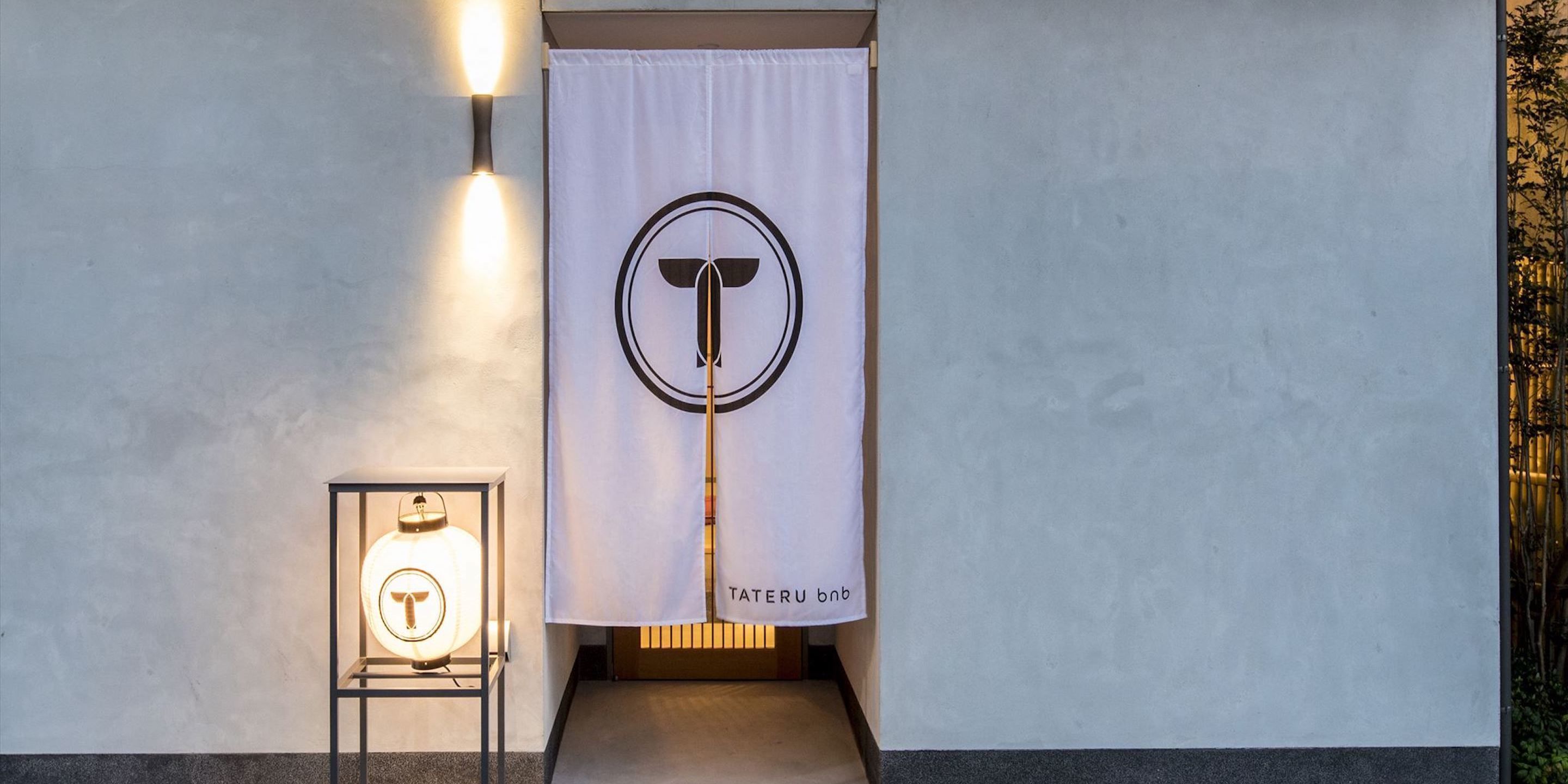 L’entrée d’un hôtel, avec un rideau blanc, un logo sur le rideau et un objet encadré sur le côté gauche.