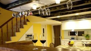 A kitchen with a wooden countertop, two wine glasses, and a staircase with hanging pots. - Starburst B&B (Dongshan)
