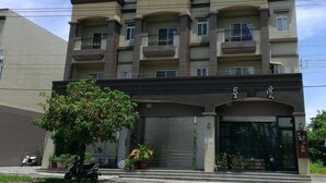 A multi-story residential building with balconies, a gated entrance, and potted plants. - Starburst B&B (Dongshan)
