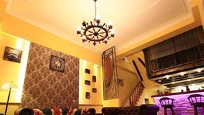 A living room with a sofa, a coffee table, a chandelier, and a staircase leading to a balcony. - Starburst B&B (Dongshan)