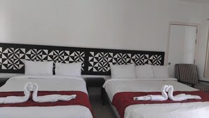 A hotel room with two beds, each with a red bedspread and white pillows. The headboard features a geometric black and white pattern. - Best View Apartments (Nadi)
