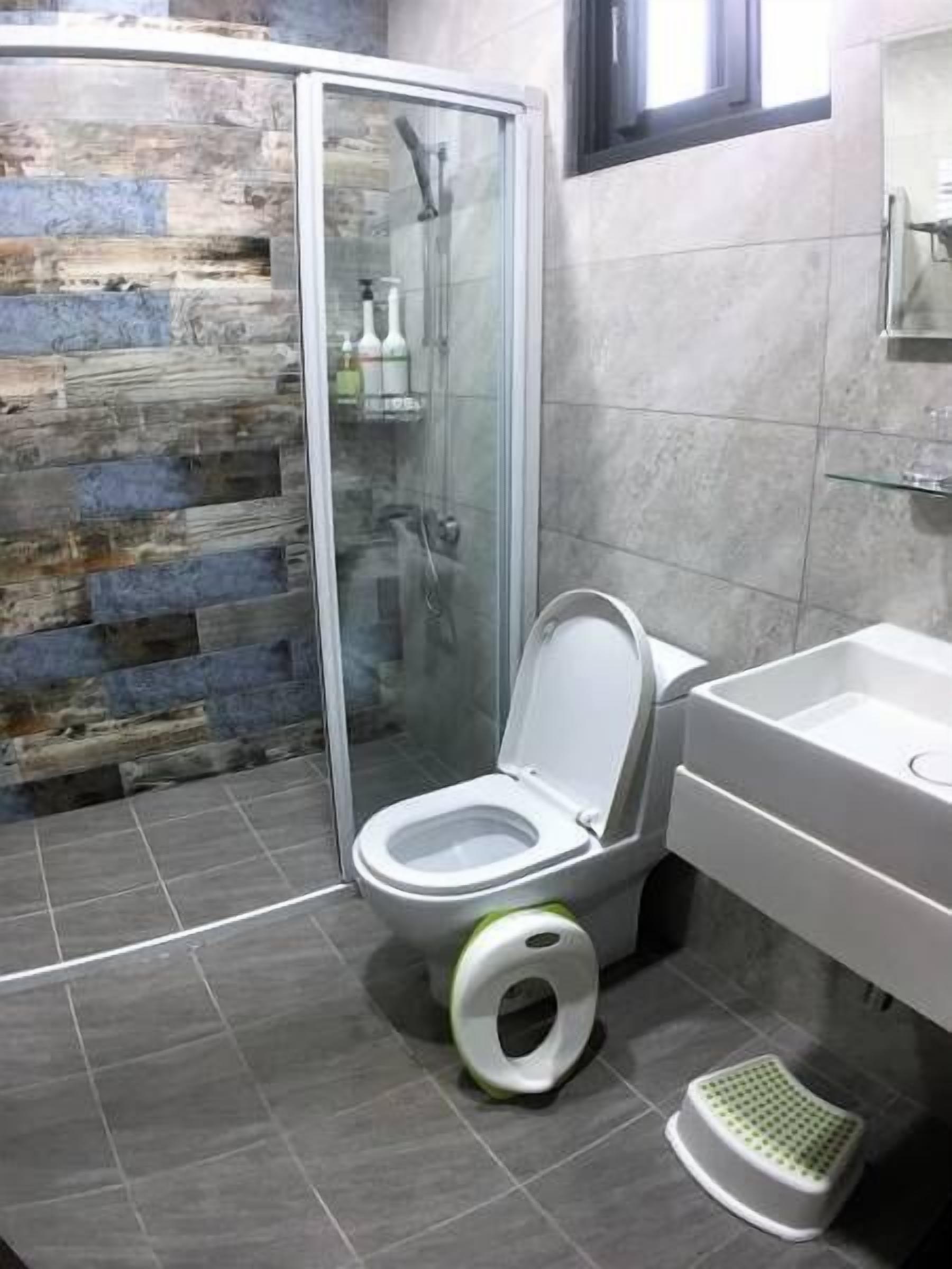 Une salle de bain moderne avec une douche à parois de verre, des toilettes équipées d’un siège bidet et un sol carrelé.