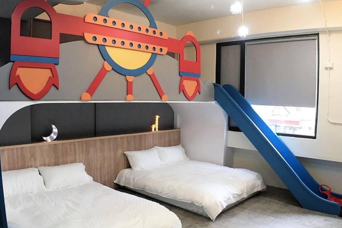 A room with two beds, a slide, and a wall decoration.