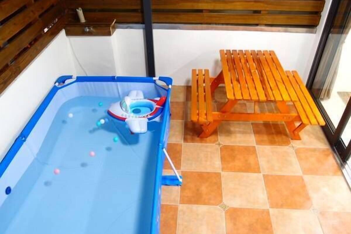 A small indoor pool with a blue border and a floating toy. Next to the pool is a wooden bench.