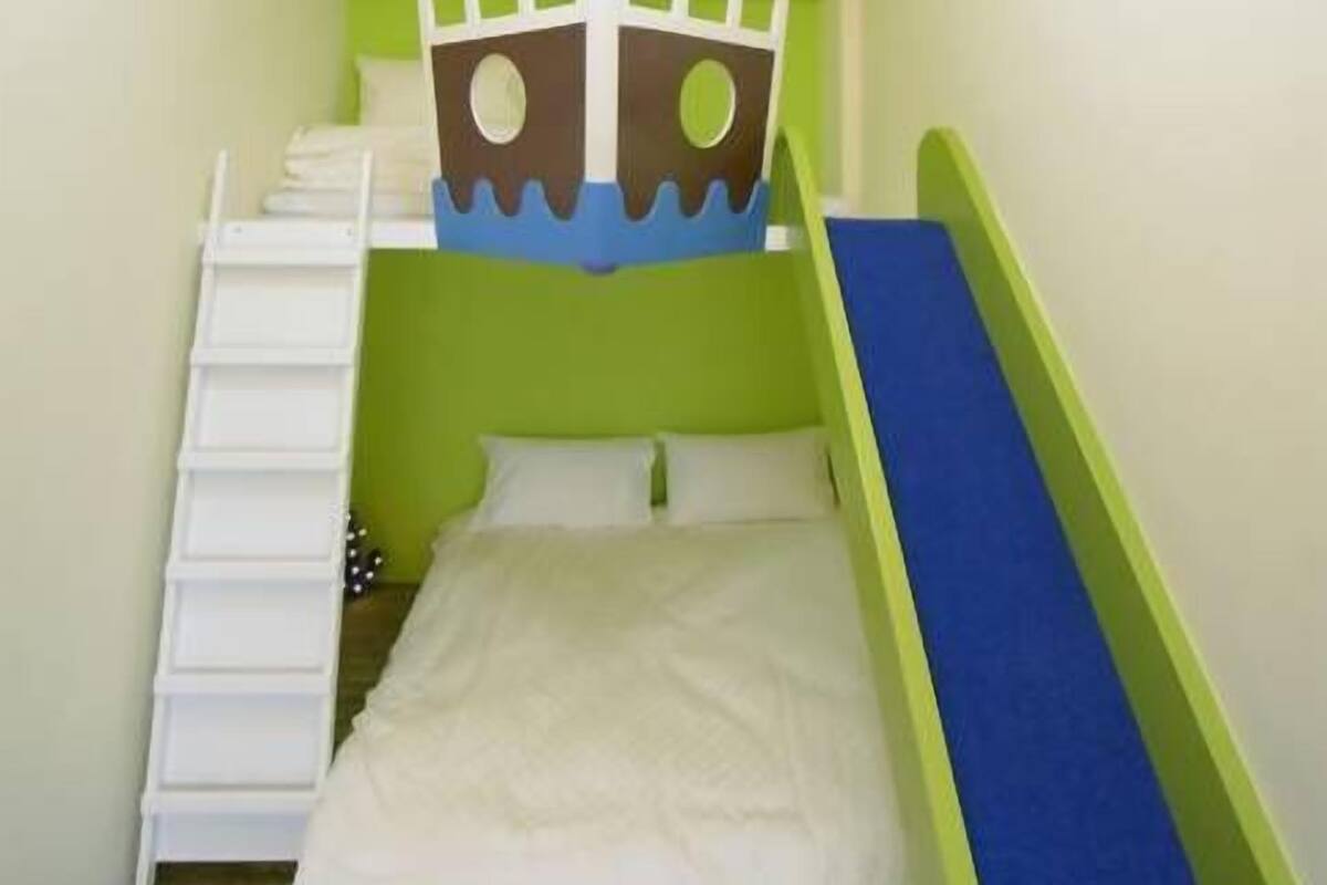 A small, brightly colored room with a bunk bed, a ladder, and a slide.