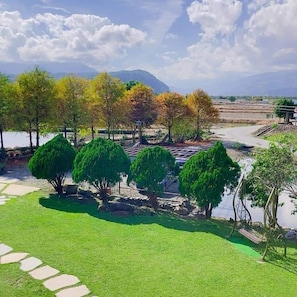 A landscaped garden with a pathway, trees, and terraced fields in the background. - Star Home (Sanxing)