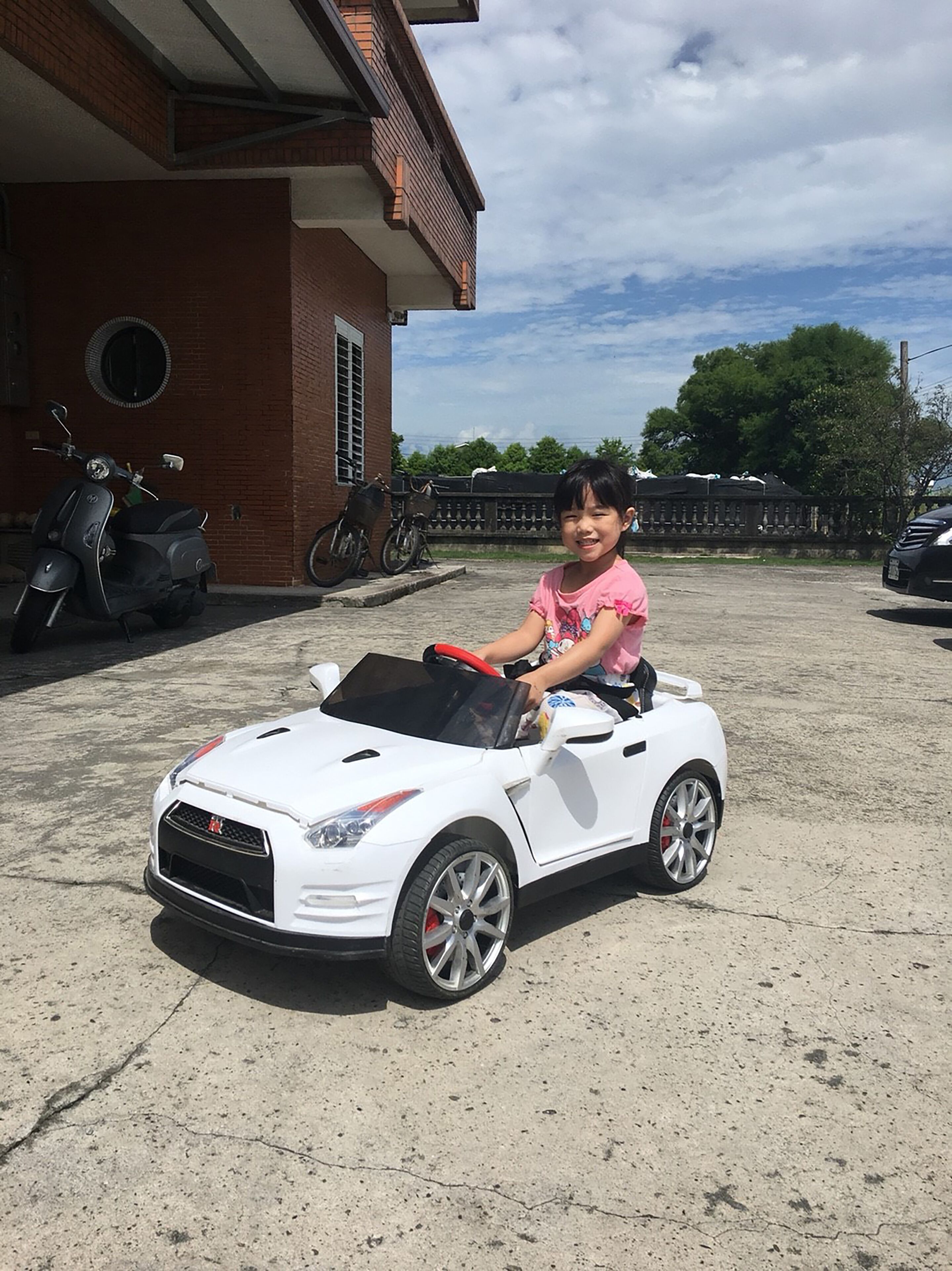 Un niño en un coche de juguete blanco.