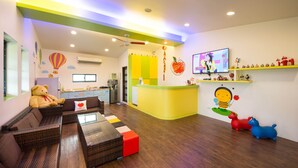 A children's play area with a sofa, a television, and a kitchen counter.