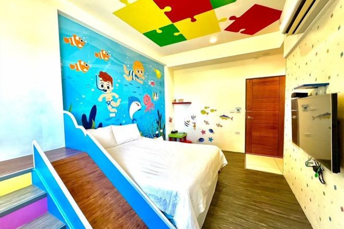 Une chambre à coucher avec un lit, une peinture murale, une porte en bois et un téléviseur.