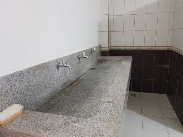 Un baño con un lavamanos de granito, dos grifos y suelo de baldosas.