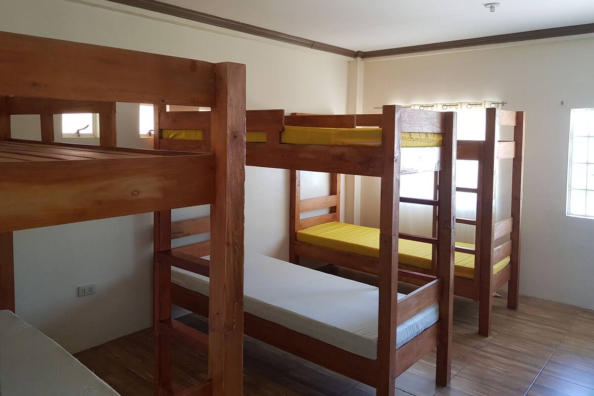 A bunk bed room with wooden frames and yellow mattresses.