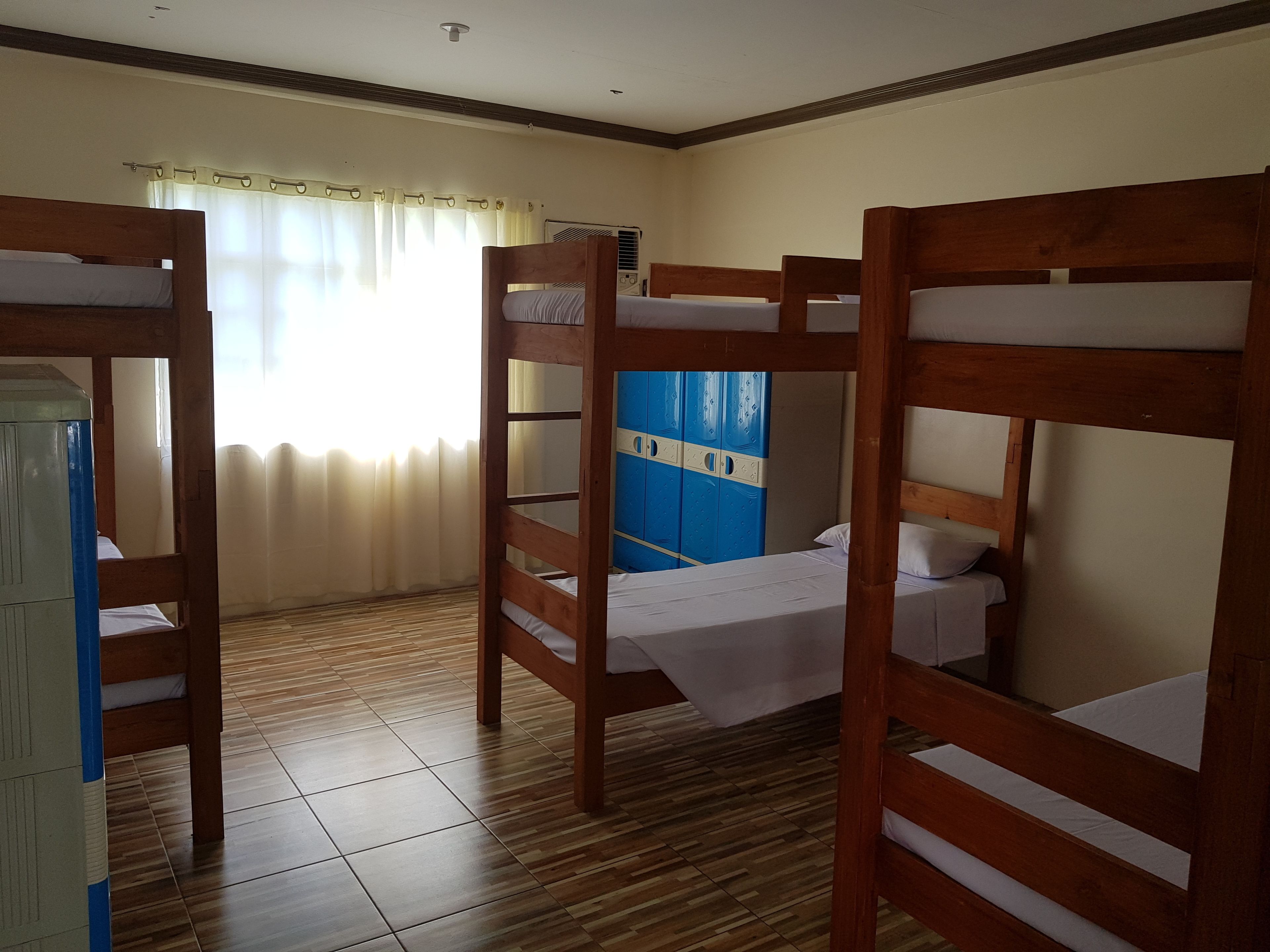 A room with bunk beds, a blue wardrobe, and a window with curtains.