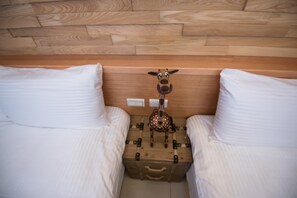 A bedroom with two beds, a wooden headboard, and a decorative moose figure on a suitcase. - Cattleya B&B (Magong)