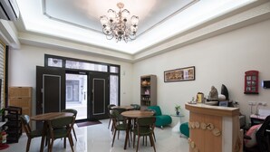 A modern interior with a dining area, a reception desk, and a large window. - Cattleya B&B (Magong)
