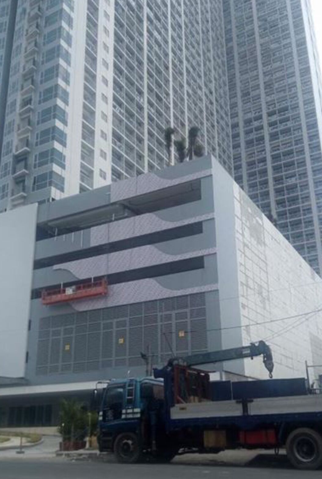 A modern building with a large glass facade and a crane parked in front.