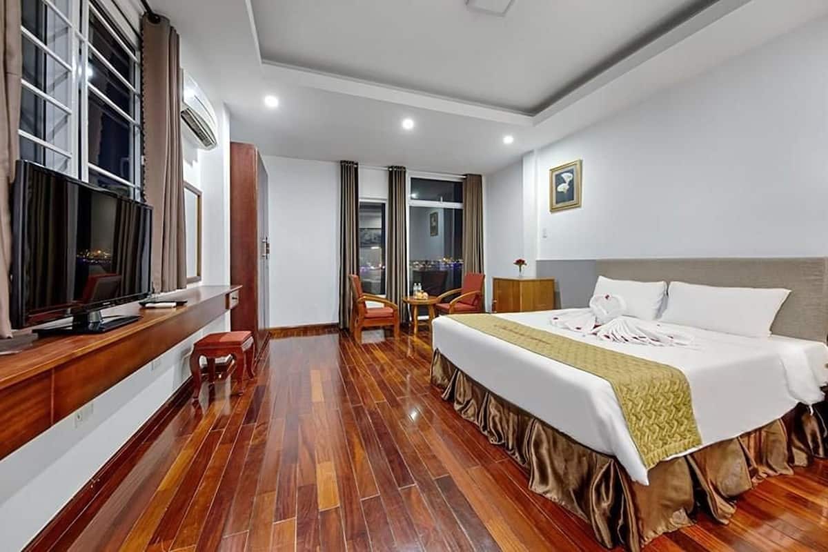 Quarto de hotel com uma cama grande, televisão, escrivaninha e uma cadeira.