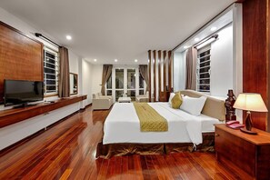 A hotel room with a large bed, a TV, a desk, and a window with curtains. - Catinal Hotel (Da Nang)
