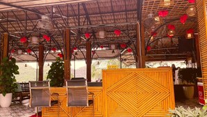 A reception area with a bamboo reception desk, seating, and a view of the outdoors. - Le Pont Bungalow Hostel (Hai Phong)