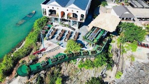 A coastal hotel with a large building featuring multiple balconies, a swimming pool, and a boat dock. - Le Pont Bungalow Hostel (Hai Phong)