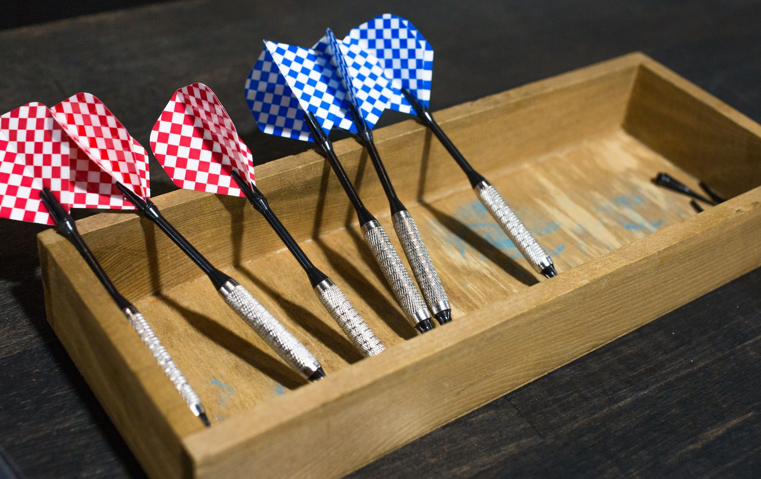 A wooden tray holding several checkered dartboards.