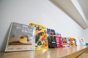 A row of books on a wooden surface against a white wall. - Merry Gate Osaka - Hostel (Osaka)