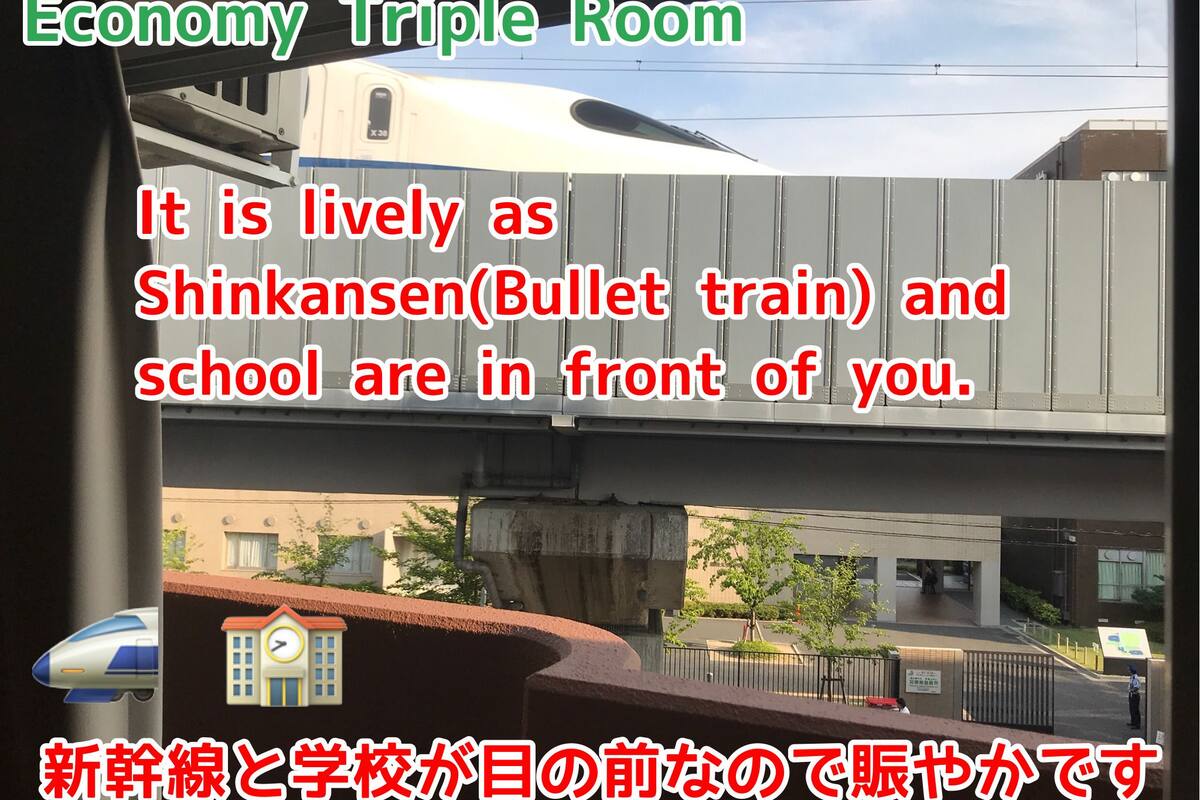 A view from a window of a building with a train passing by, a school, and a pedestrian bridge.