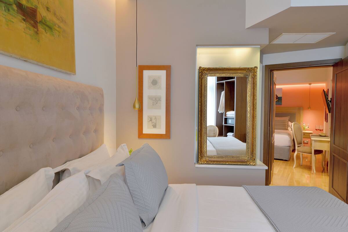 A hotel room with a large bed, a mirror, and a framed picture on the wall.