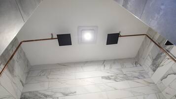 Een badkamer met een wit plafond, een marmeren vloer en een zichtbare douchehoek.